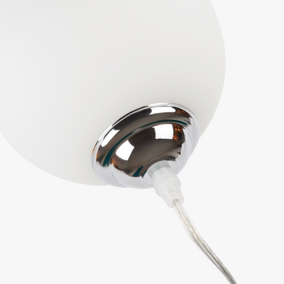 Lyra table lamp with frosted glass globe held by a coiled metal sculptural base